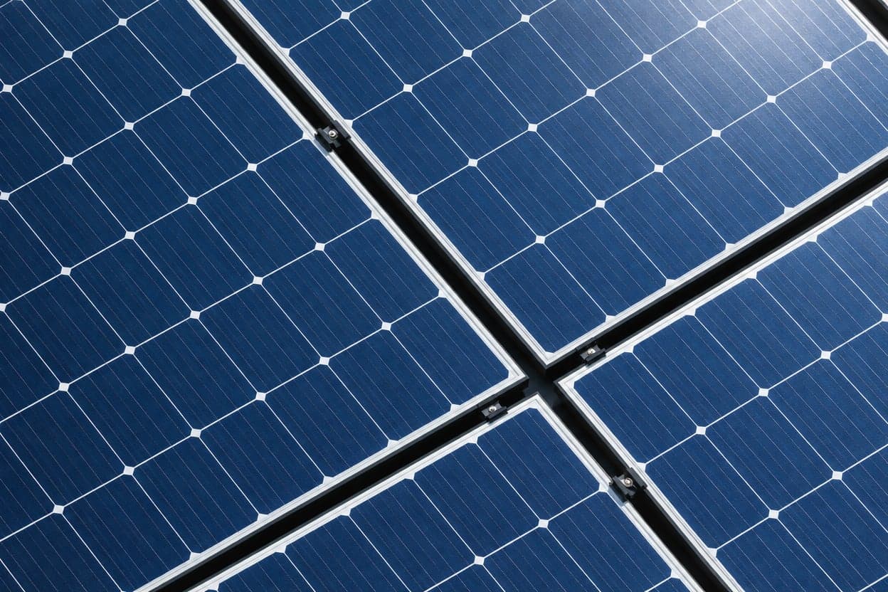 Close-up of four solar panels meeting at a corner, their blue cells divided by thin white lines